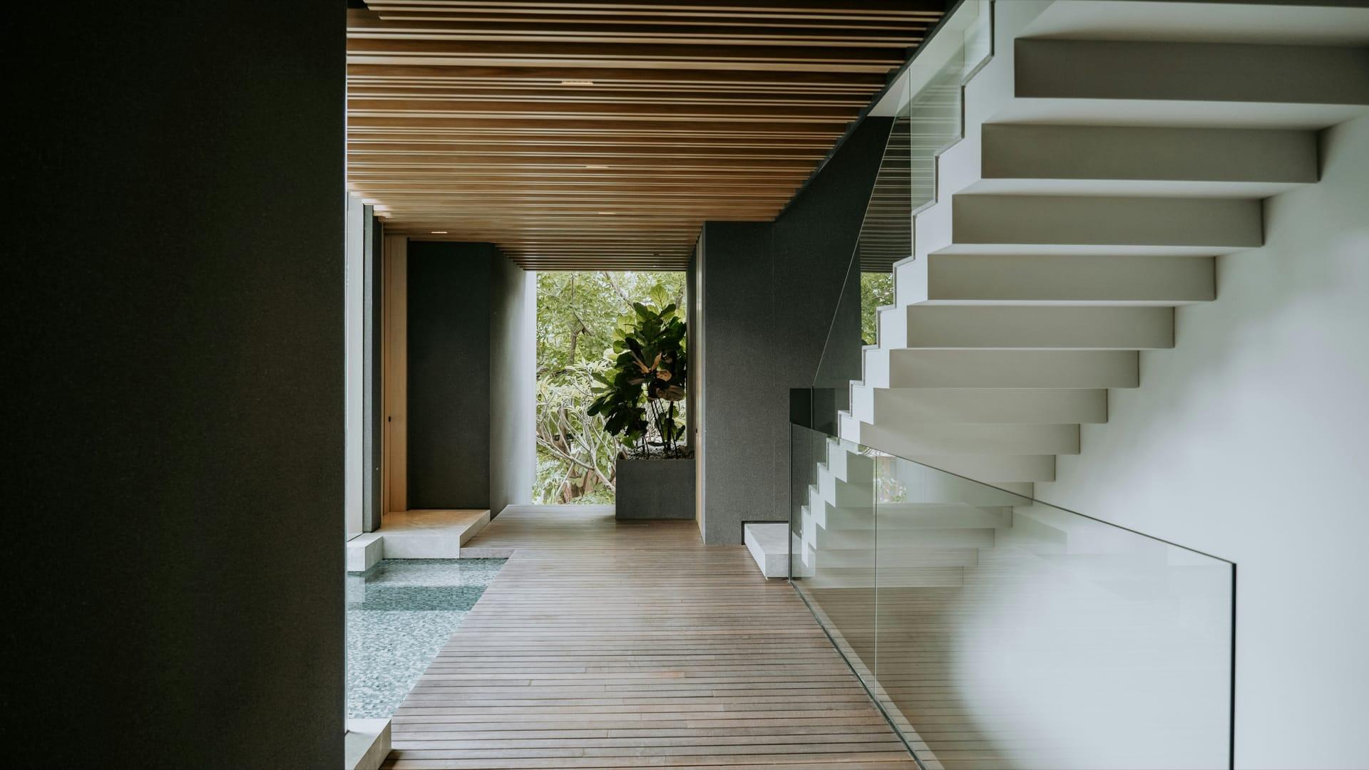 Moderne freitragende Treppe mit Glasgeländer in einem Flur mit Holzdecke und Holzboden